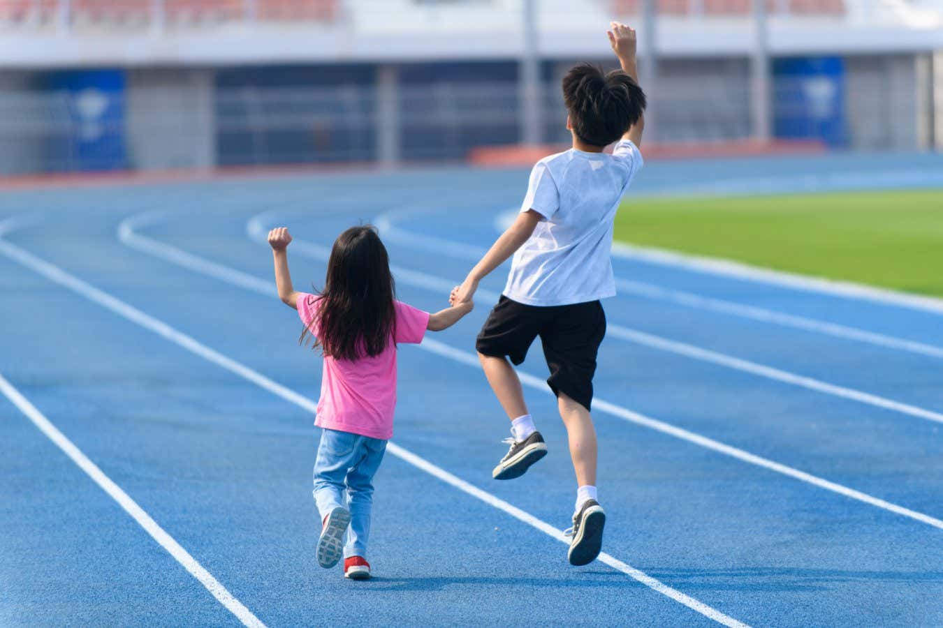 Young boy and girl play on a bluetrack after running in summer; Shutterstock ID 1660158184; purchase_order: -; job: -; client: -; other: -